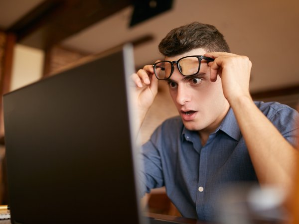Mann schaut auf Laptop-Bildschirm und ist sehr überrascht