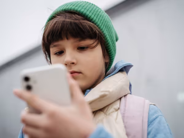 Ein Mädchen blickt auf das Handy, das sie vor sich in der Hand hält.