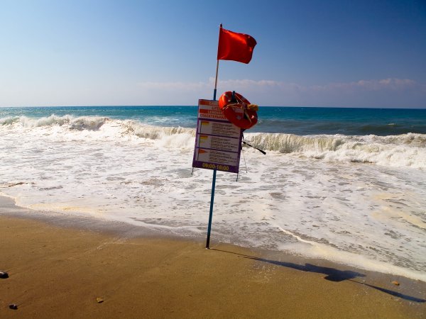 Stürmischer Strand mit Warnhinweis und roter Fahne