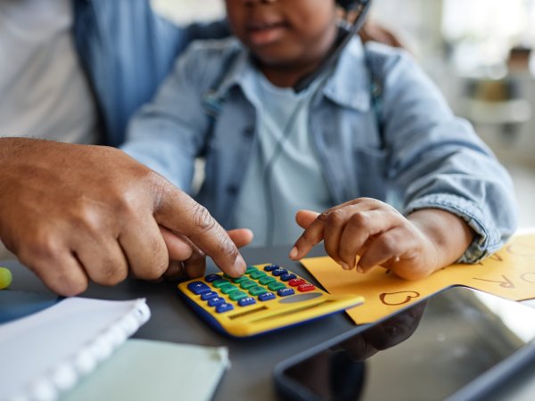 Vater und Kind spielen mit einem Spielzeug-Taschenrechner 