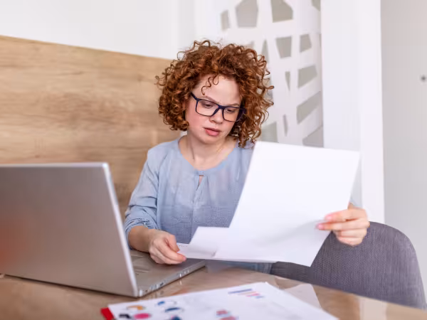 Eine Frau sitzt an ihrem Laptop und schaut auf eine Rechnung