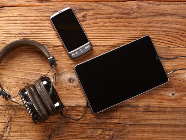 Kopfhörer, Handy und Tablet liegen auf Tisch