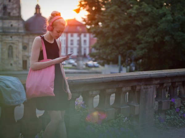 Junge Frau sieht auf ihr Handy. Quelle: Rehvolution.de / photocase.de