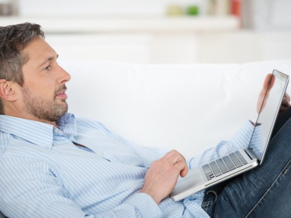 Mann mit Laptop auf Sofa; Quelle: contrastwerkstatt - fotolia.com