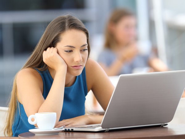 Genervte Frau wartet vor dem Laptop vergelblich auf das Laden von Inhalten