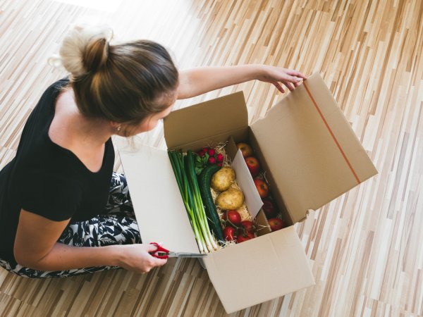 Frau öffnet Paket mit Lebensmitteln