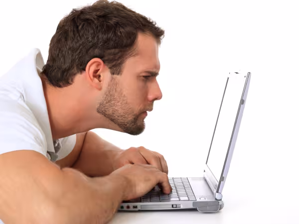 Mann hält seinen Kopf nah vor Laptop und liest 