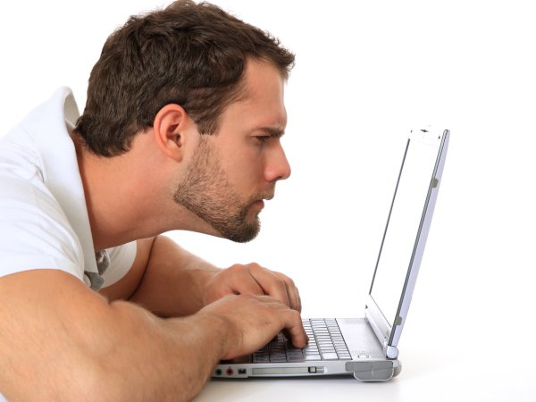 Mann hält seinen Kopf nah vor Laptop und liest 