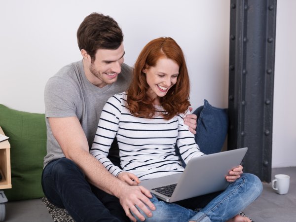 Junges Paar bucht eine Reise auf einem Online-Portal.