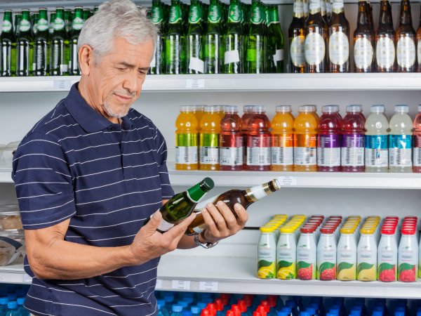 Mann vergleicht Nährwertangaben auf Bierflaschen. Foto: Tyler-Olson - Adobe Stock