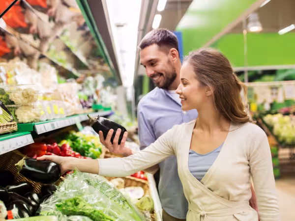 Personen stehen in Gemüseabteilung eines Supermarktes 