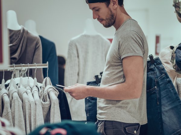 Mann im Modeladen betrachtet Preisschild