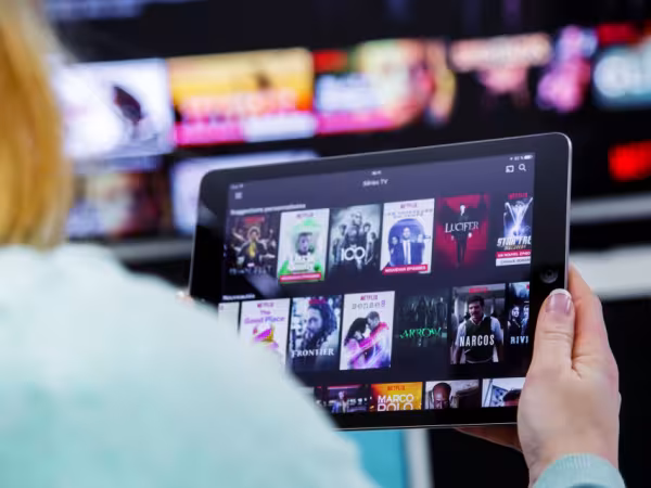 Person sitzt vor Tablet und vor Fernseher 