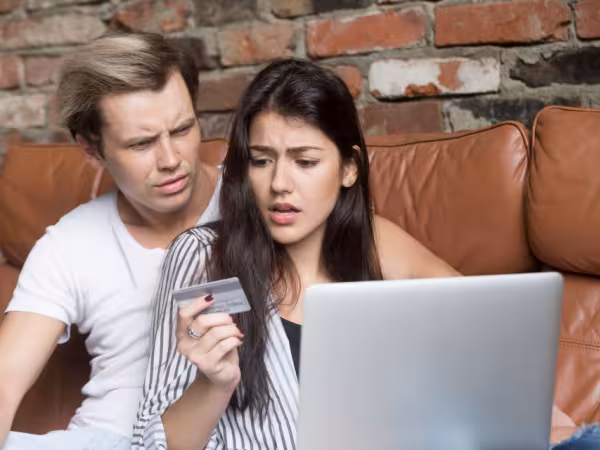 Ein Mann und eine Frau sitzen auf dem Sofa vor einem Laptop