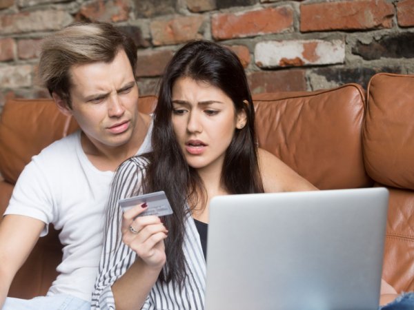 Ein Mann und eine Frau sitzen auf dem Sofa vor einem Laptop