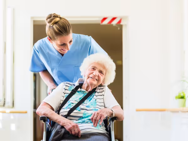 Pflegerin mit Seniorin im Rollstuhl.