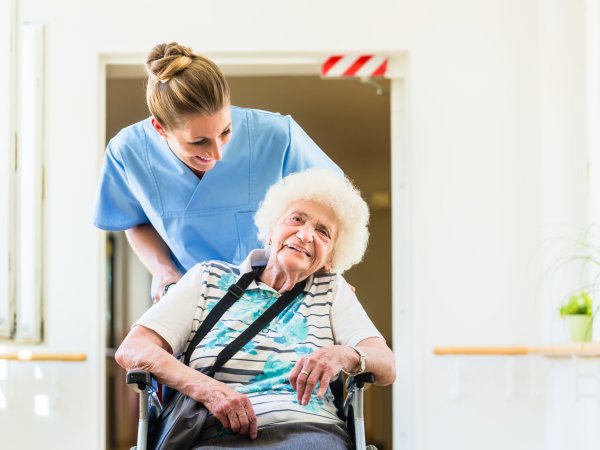 Pflegerin mit Seniorin im Rollstuhl.