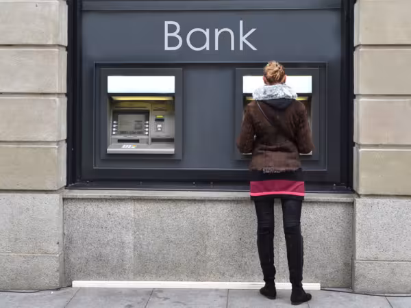 Junge Frau holt bei einer Bank Geld am Geldautomaten