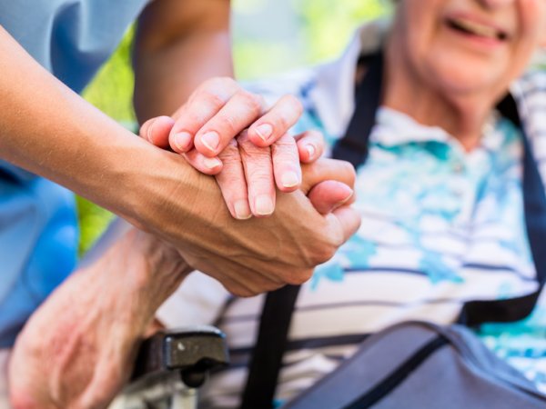 Alte und junge Person halten Hände