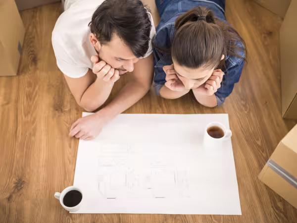 Paar in Neubauwohnung sieht sich Bauplan an. 