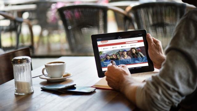 Eine Person, die ein Tablett in der Hand hält, auf der die Webseite des vzbv zu sehen ist.